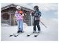 Kinder in CRIVIT Skijacken im Schnee vor einer Holzhütte.