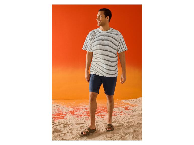 Lächelnder Mann im gestreiften ESMARA MEN T-Shirt und Shorts am Strand.