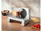 Elektrische Aufschnittmaschine mit Käse, Brot und Tomaten auf einer Holzküchenarbeitsplatte.