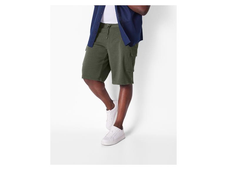 Mann trägt olivgrüne Cargo-Shorts und weiße Sneaker.