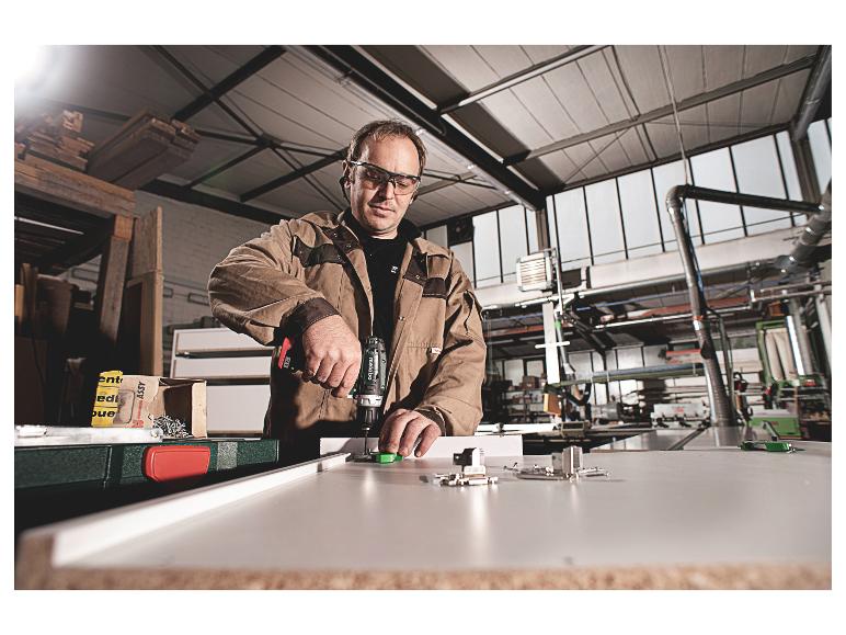 Mann benutzt Akkuschrauber in einer Holzwerkstatt