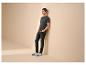 Mann in dunkelgrauem T-Shirt mit 'LIFE BEGINS' Text, schwarzen Jeans und weißen Sneakern.