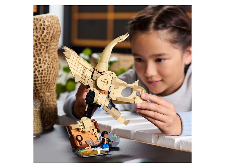 Ein Mädchen baut ein LEGO Dinosaurierskelett zusammen, mit einer LEGO Minifigur daneben.