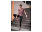 Frau in lila und schwarzer Sportkleidung macht Yoga auf einer grauen Matte.