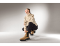 Frau in beigem Pullover, schwarzer Hose und braunen Wildleder-Stiefeletten.