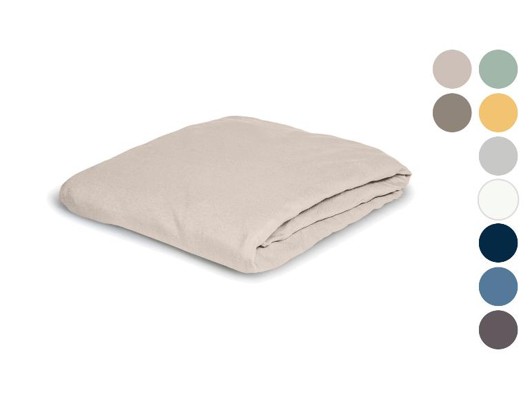 Gefaltetes beiges Spannbettlaken mit passenden Farbmustern.