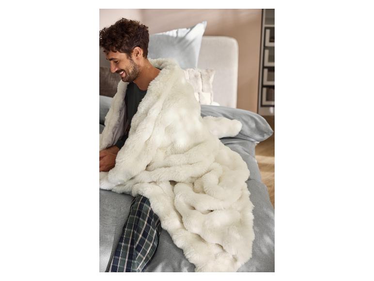 Mann im Pyjama, eingekuschelt in eine Premium-Decke von LIVARNO® auf dem Bett.