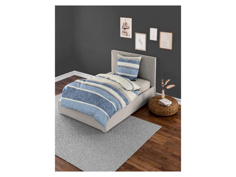 Ein Bett mit einer blauen, gestreiften Bettdecke und einem passenden Kissen.