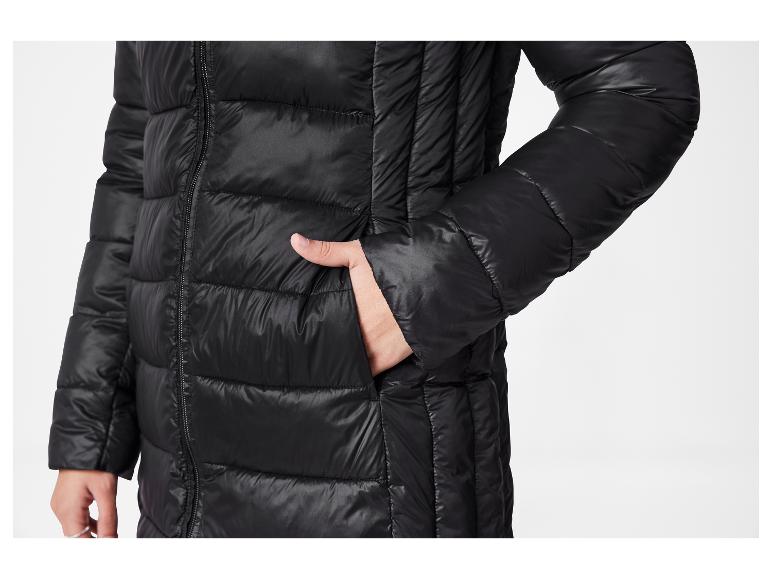 Schwarze lange Steppjacke mit einer Hand in der Tasche.
