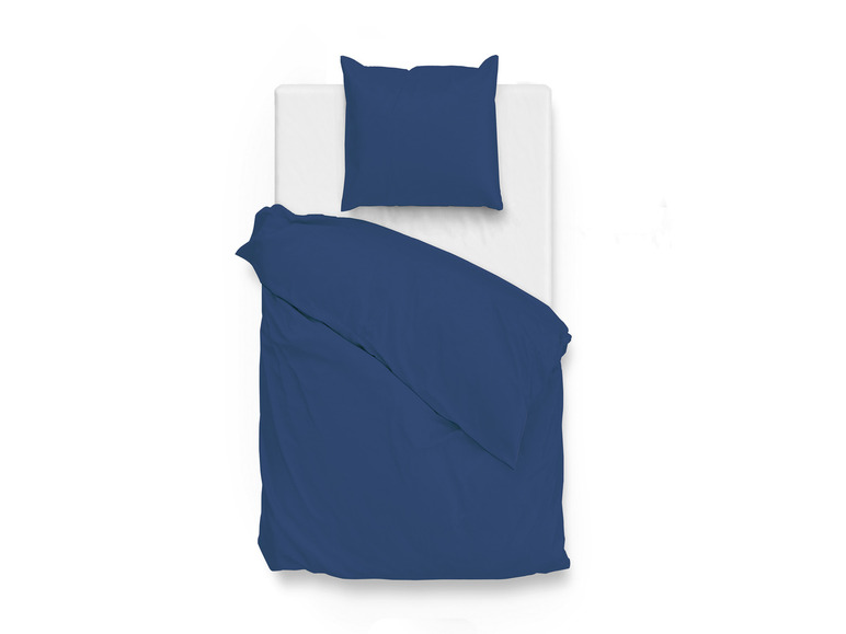 Ein dunkelblauer Bettbezug und Kissenbezüge auf einem weißen Bett.