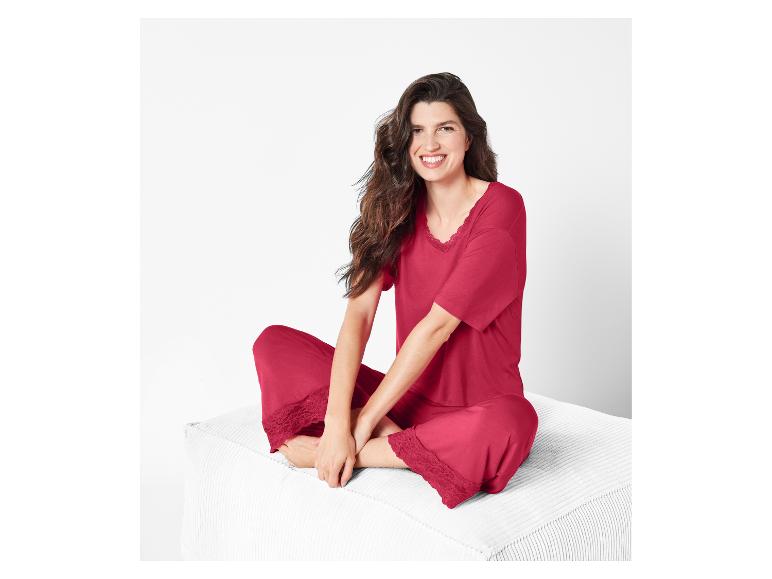 Frau in rotem Pyjama mit Spitze, sitzend auf einer weißen Couch.