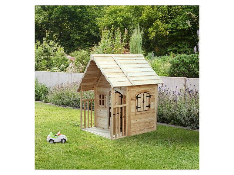 Holzspielhaus mit kleinem Spielzeugauto in einem grünen Garten.