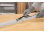 Arbeitshandschuhe schneiden ein Metallprofil mit einem Rotationswerkzeug.