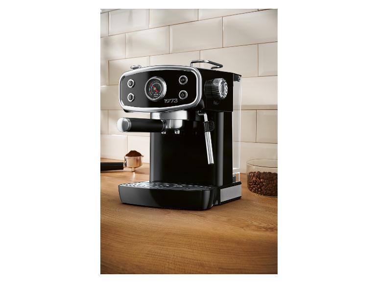 Schwarze Espressomaschine auf Holztisch mit Kaffeebohnen und gemahlenem Kaffee