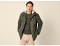 Mann in grünem Parka mit Kapuze, dunkelgrünem Pullover und beiger Hose.