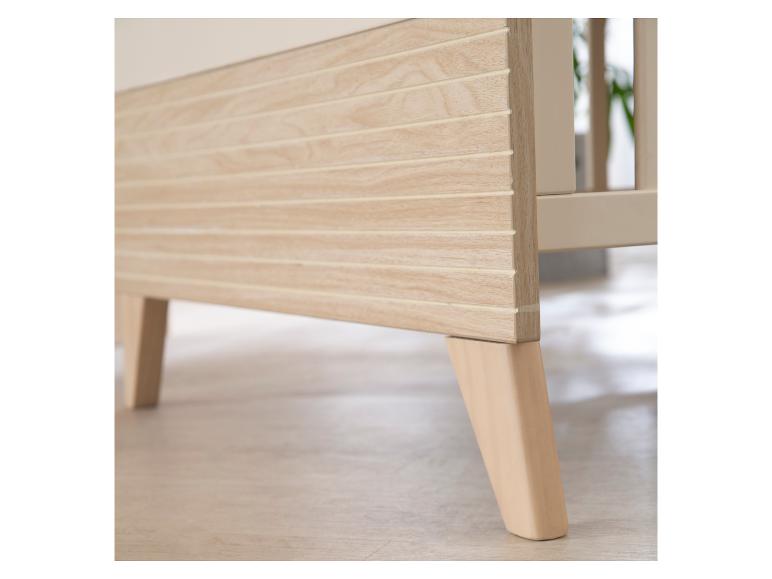 Helle Holzbeine und Seitenwand eines Babybetts.