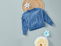 Ein blauer Pullover mit Spitzendetails, ein Rattan-Untersetzer und blaue Blumen.
