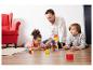 Vater und Kinder spielen auf dem Boden mit Lernbausteinen und Karten.