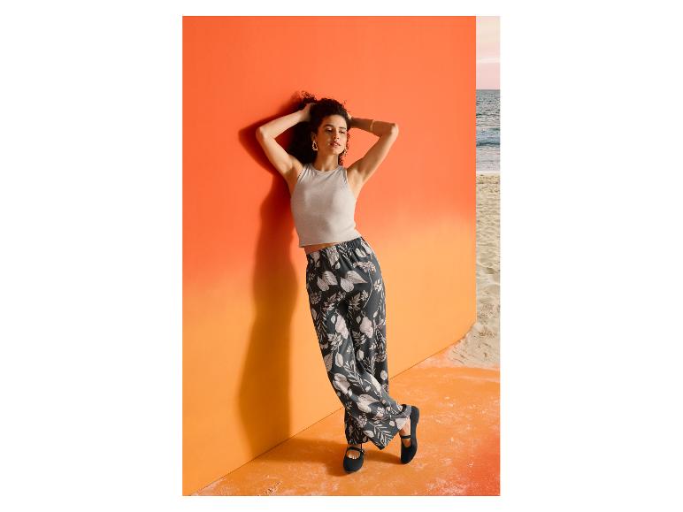 Frau im grauen ESMARA Ripp-Top und gemusterter Hose an einer orangefarbenen Wand.