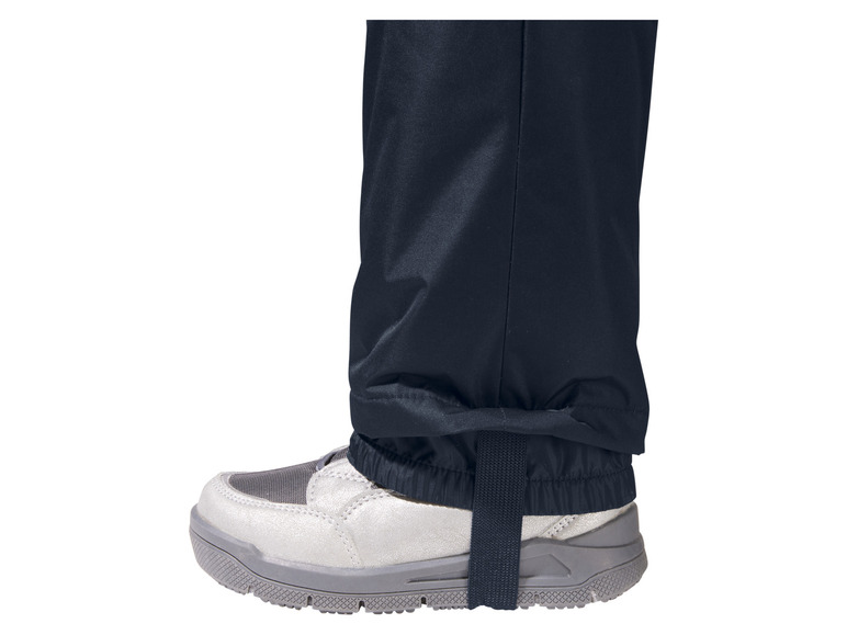Blaue Hosenbeine mit verstellbarem Gurt und grauen Turnschuhen.