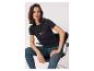 Frau in dunklem T-Shirt mit Aufdruck und Jeans, auf einem Stuhl sitzend.