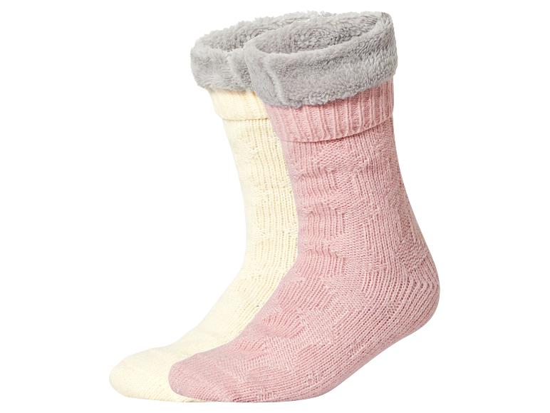 Zwei Paar gestrickte Socken, eine cremefarbene und eine rosa, mit flauschigen grauen Bündchen.