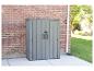 Grauer Gartenschrank mit Doppeltüren, an einer Ziegelwand stehend.