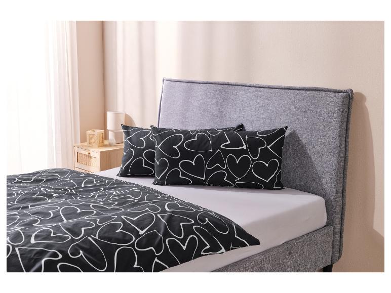 Ein Bett mit schwarzer Bettwäsche und Kissen mit einem weißen Herzmuster.