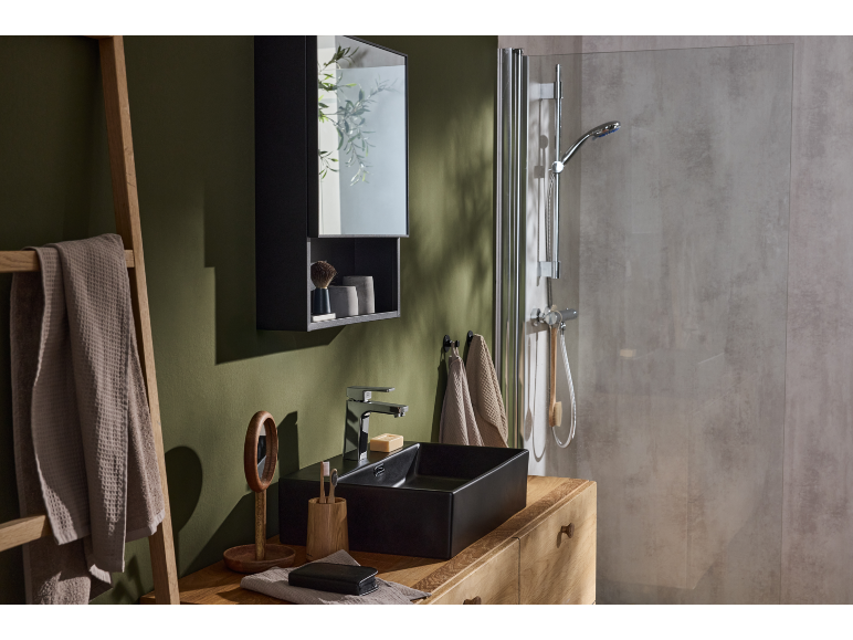 Badezimmer mit grüner Wand, schwarzem Waschbecken und Duschkabine.