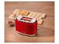 Roter Toaster mit zwei Toastscheiben, Marmelade und einem Streichmesser auf einem Holztisch.