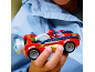 Ein Kind hält ein rot-blaues Spielzeugauto mit einer kleinen Figur darin.