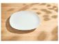Leerer weißer Teller auf einem Holztisch mit Blattschatten
