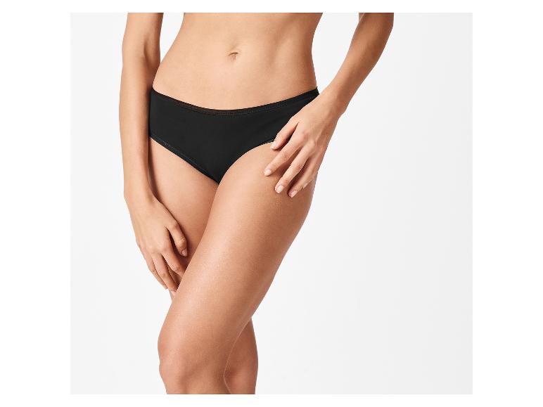Frau in schwarzen Baumwollslips, mit gekreuzten Händen auf den Beinen.