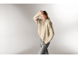 Frau in beigem Rollkragenpullover und grauer Hose.