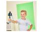 Junge filmt ein Video mit einer Kamera auf einem Stativ vor einem Greenscreen.