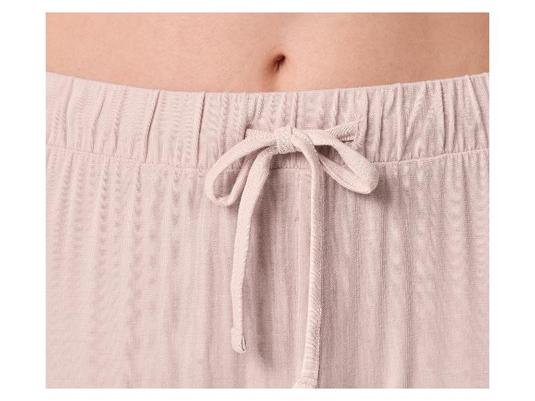 Nahaufnahme des Bauches einer Frau in hellrosa Pyjamahose mit Kordelzug.