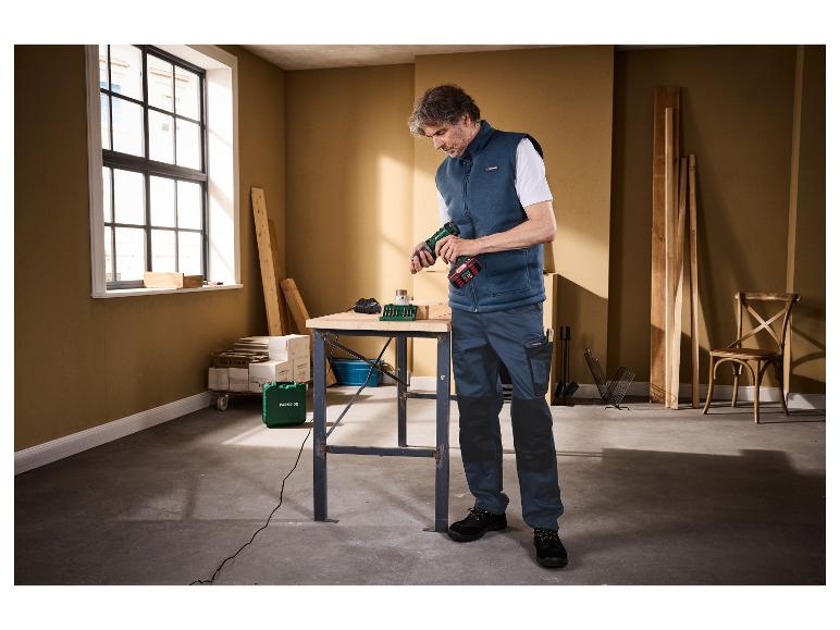Mann in Parkside-Weste und Arbeitshose benutzt einen Parkside-Bohrer in einer Werkstatt.