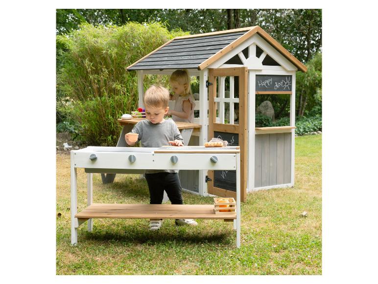Zwei Kinder spielen mit einer Outdoor-Spielküche und einem Spielhaus im Garten.