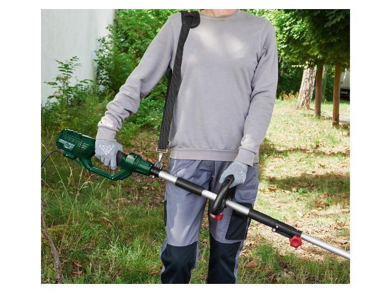 Person benutzt elektrische Heckenschere mit Tragegurt im Garten.
