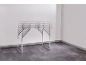 Klapptisch mit grauer Platte und Metallrahmen in einem leeren Raum.