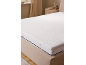 Weißer Matratzentopper auf einem Bett in einem neutralen Schlafzimmer.