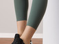 Grüne Leggings mit gewelltem Saum und schwarzen Sneakern.