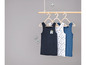 Drei Tanktops für Jungen, eines einfarbig blau, eines weiß mit Druck und eines einfarbig blau.