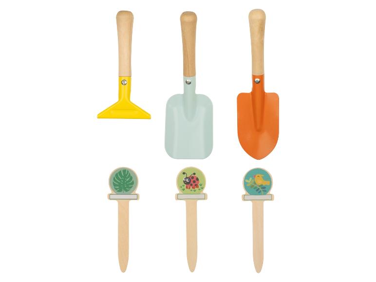Ein gelber Rechen, eine blaue und eine orange Schaufel und drei Pflanzen-Sticks.