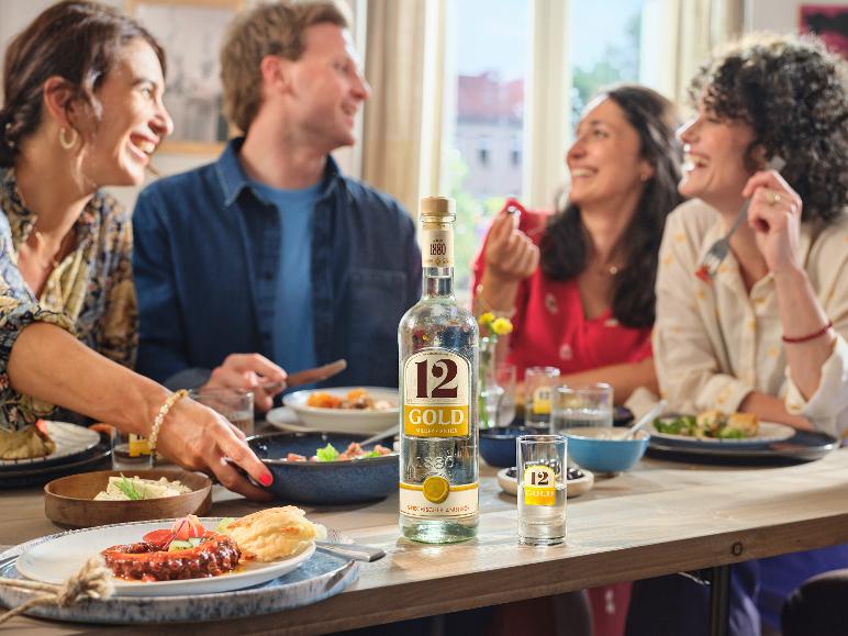 Freunde essen zu Abend mit einer Flasche griechischem Anislikör und Schnapsgläsern auf dem Tisch.