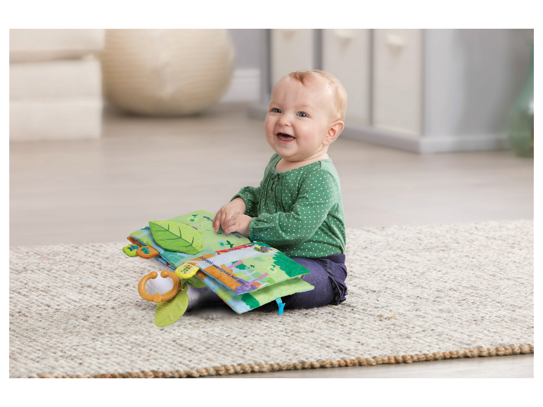 Baby mit einem Tiny Love Stoffbuch.