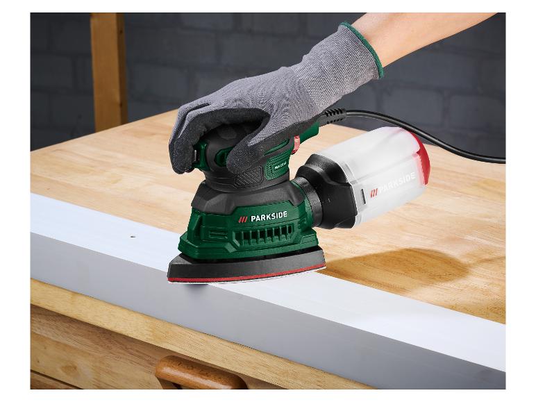 Behandschuhte Hand schleift ein weißes Brett mit einem Parkside Schleifer auf einem Holztisch.