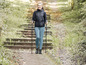 Eine Frau in Wanderkleidung geht mit Stöcken auf einem Weg.