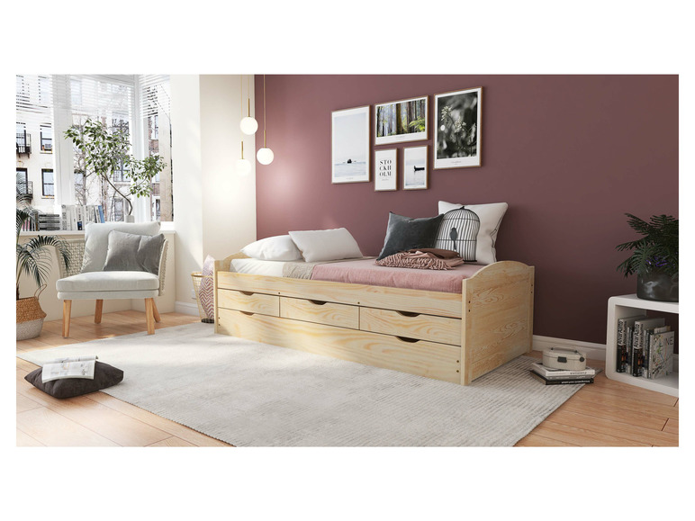 Ein Holzbett mit Schubladen in einem Schlafzimmer mit einem Stuhl.