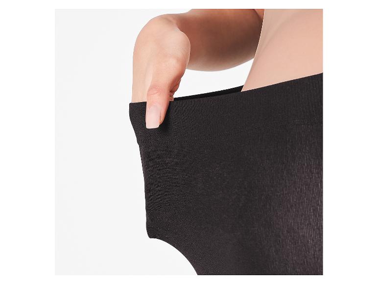 Eine Hand zieht am Bund einer schwarzen Leggings und zeigt die Elastizität.